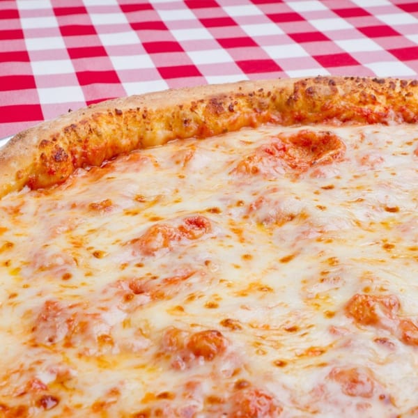 Close-up of a cheese pizza with browned crust and tomato sauce, served on a red-and-white checkered tablecloth.