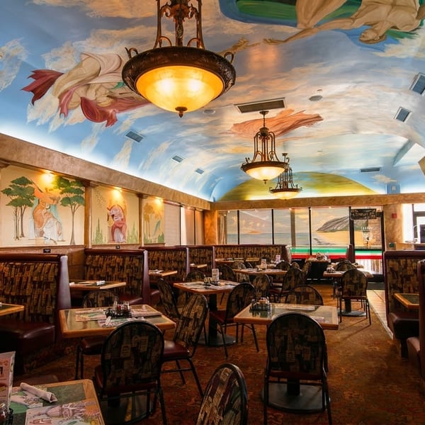 Restaurant interior with ornate chandeliers, painted murals on walls, and a sky-themed ceiling.