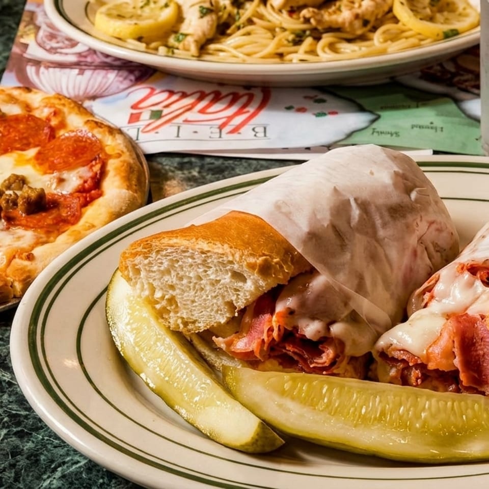 A pepperoni and sausage pizza, a sub sandwich with pickles, and pasta with lemon slices.