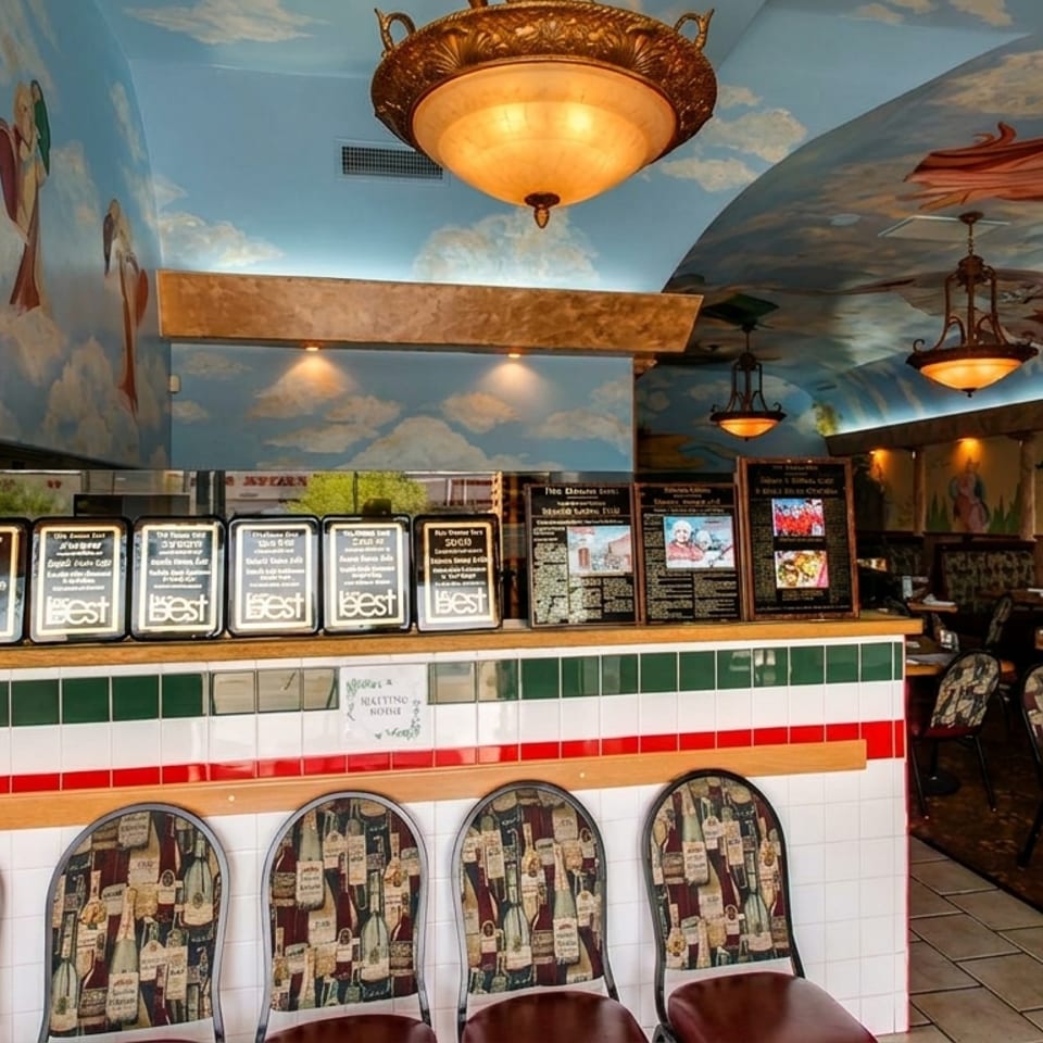 Restaurant interior with a sky-painted ceiling, murals, awards, and a counter with bar stools.